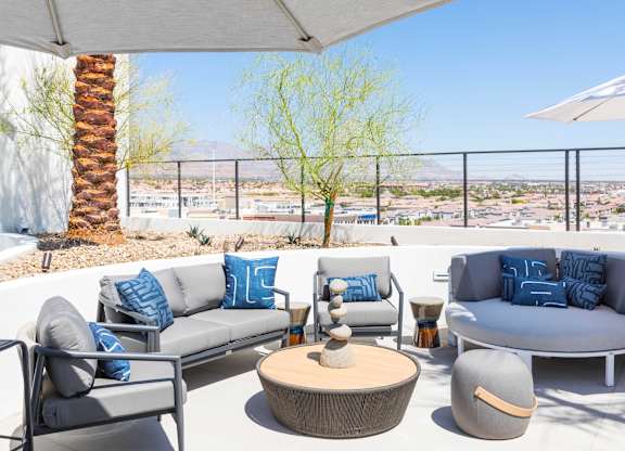 A patio with grey couches and a wooden table.