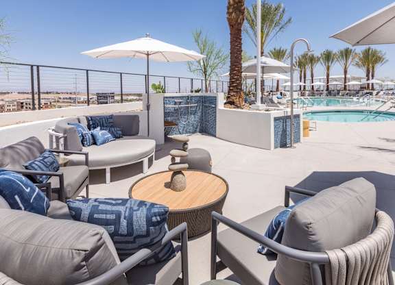 A poolside seating area with a view of the pool and palm trees.
