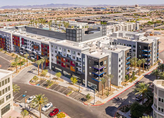 A modern multi-story building with a parking lot in front.