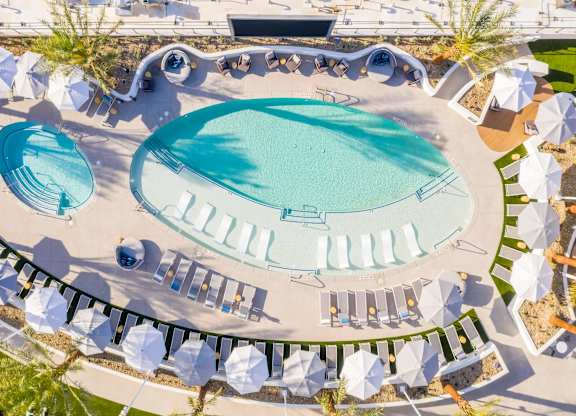 An aerial view of a pool surrounded by lounge chairs and umbrellas.