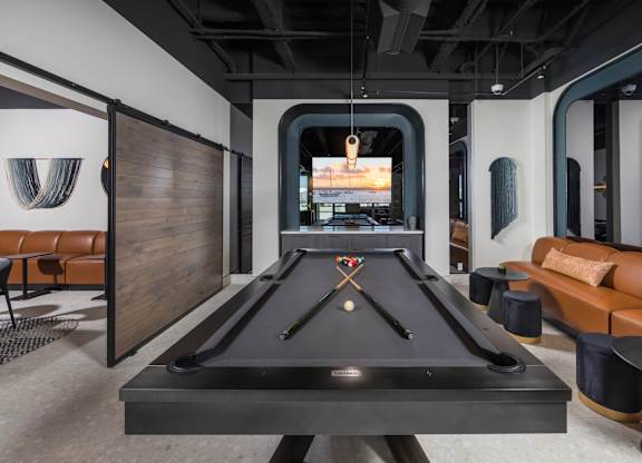 A pool table is in the middle of a room with a couch and a chair.