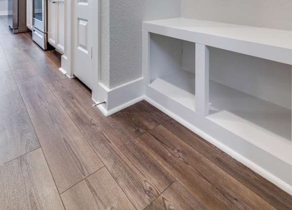 a renovated kitchen with white cabinets and a wood floor