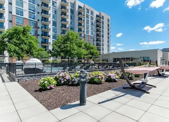 A modern outdoor seating area with a bench and a table surrounded by a flower bed.