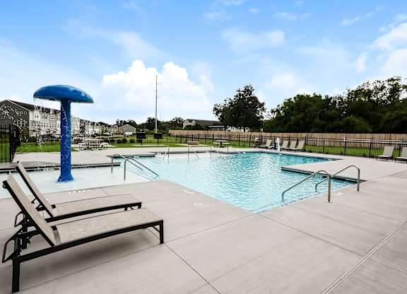 A pool with a blue umbrella and a sun lounger.