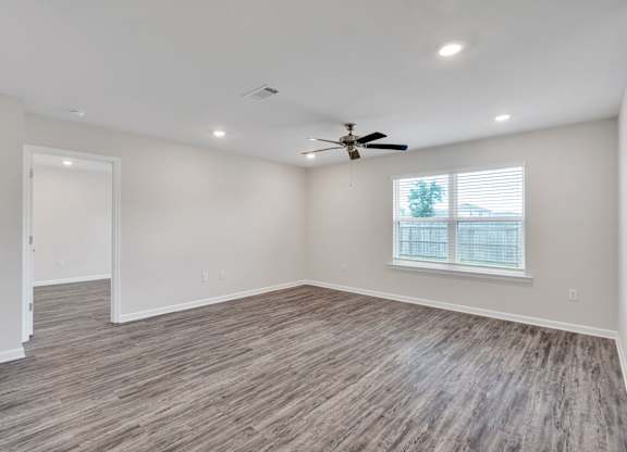 A room with a ceiling fan and a window with blinds.