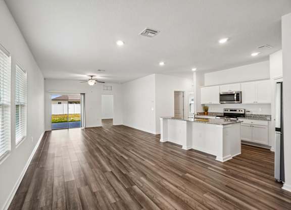 A spacious kitchen with white cabinets and a wooden floor.