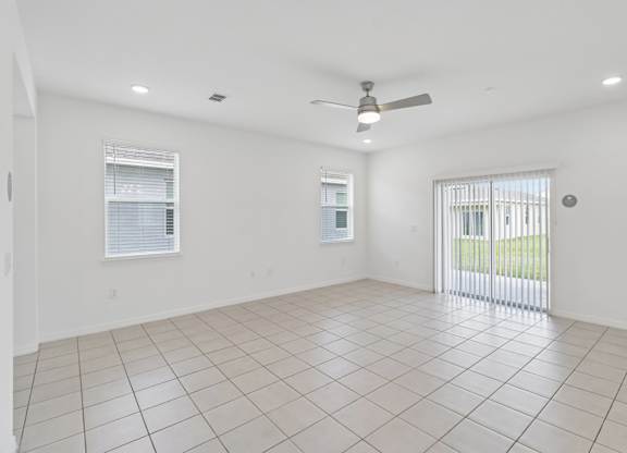 A spacious room with a ceiling fan and tiled flooring.