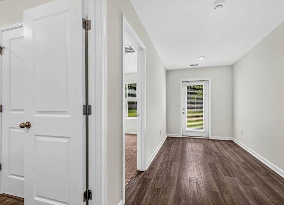 A hallway with white doors and a wooden floor.
