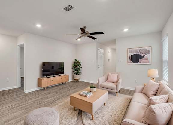 A living room with a ceiling fan and a flat screen TV.
