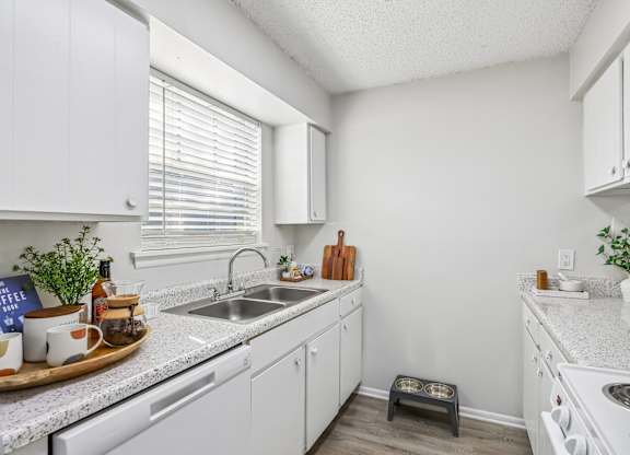A kitchen with white cabinets and a white stove top oven.