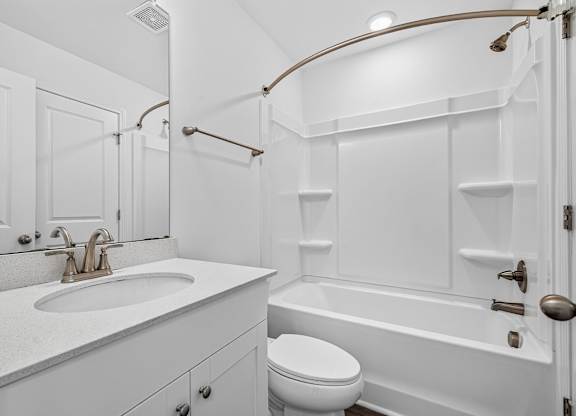 A white bathroom with a toilet, sink, and bathtub.