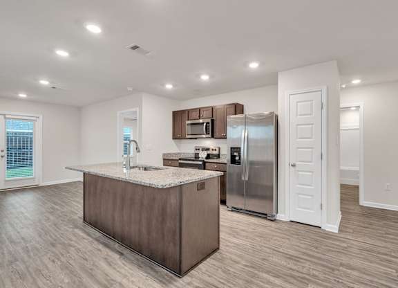 A kitchen with a refrigerator, microwave, and sink.
