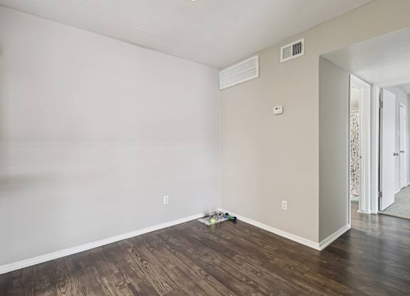 A room with wooden flooring and white walls.