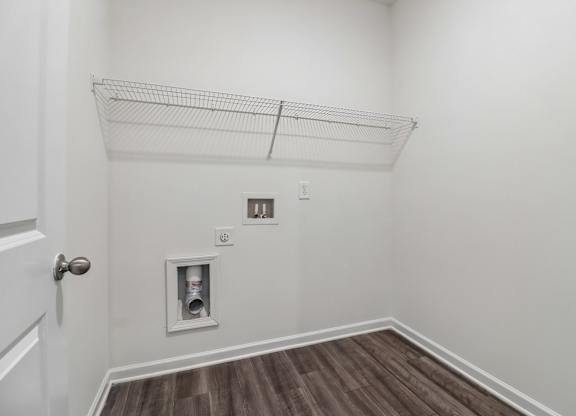 A white wall with a door and a shelf above it.