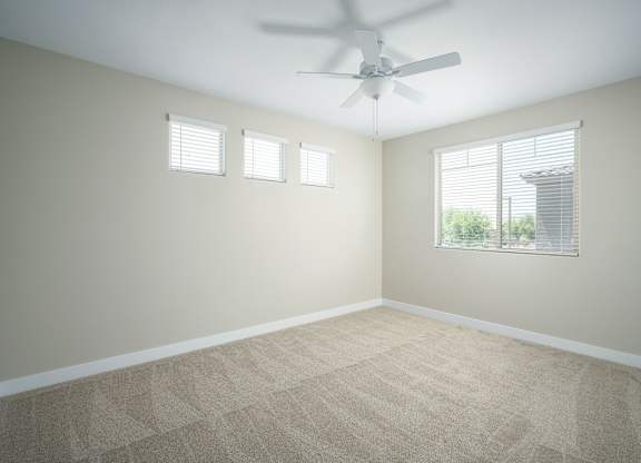 A room with a ceiling fan and carpeted floor.