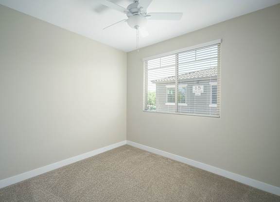 A room with a ceiling fan and a window with blinds.