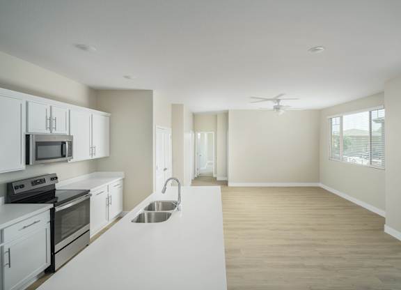 A kitchen with white cabinets and a stainless steel sink.