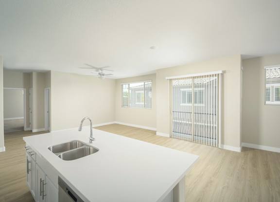 A kitchen with a white countertop and a stainless steel sink.