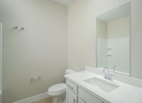A white bathroom with a toilet, sink, and mirror.