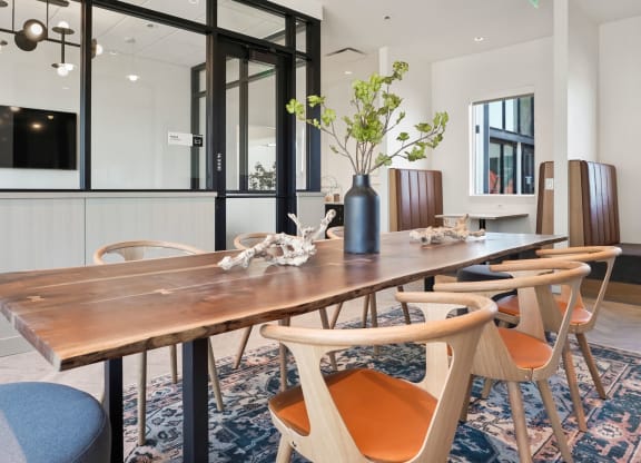 a dining room with a long wooden table and orange chairs