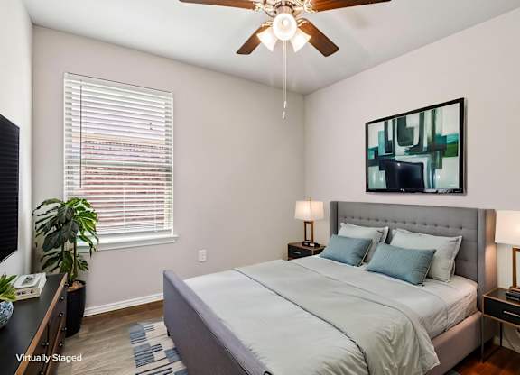 A bedroom with a bed, nightstands, and a ceiling fan.