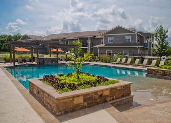 A large swimming pool surrounded by a stone planter with plants in it.