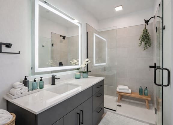 A modern bathroom with a white countertop and a large mirror.