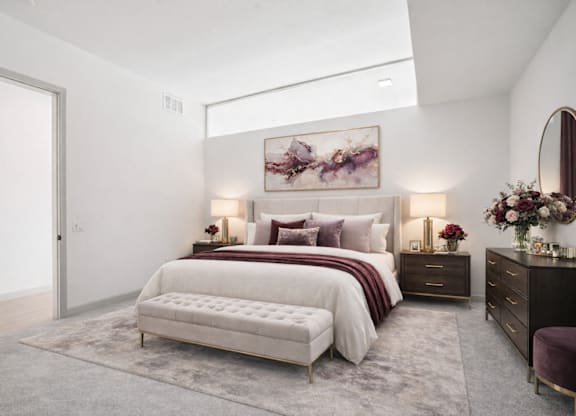 A bedroom with a large bed, a bench, and a painting on the wall.