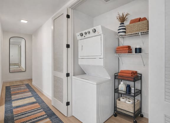 A white laundry room with a washer and dryer, a basket, and a striped rug.