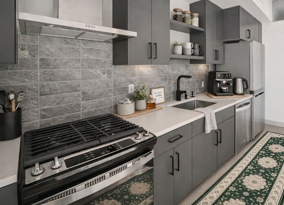A modern kitchen with a black stove top oven and grey cabinets.