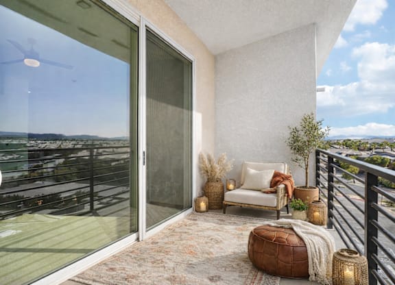 A balcony with a chair and a table with a view of the city.
