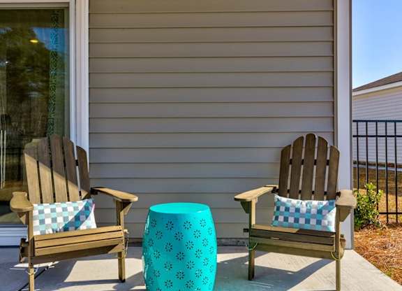 Houses for Rent in Myrtle Beach, SC - The Palmer at Carolina Forest - Spacious Private Patio With a Fenced Yard, Two Wooden Armchairs, and a Blue Side Table