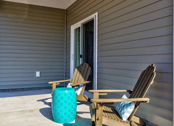 a pair of adirondack chairs sit on a patio in front of a door