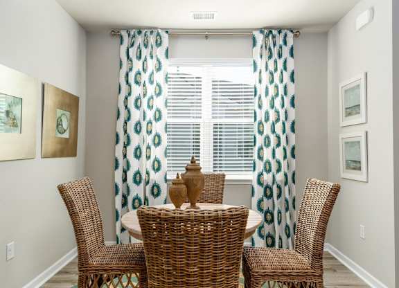 a round table with four chairs in front of a window with curtains