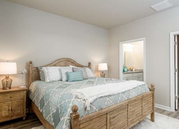 Myrtle Beach Rental Homes - The Palmer at Carolina Forest - Bedroom with Vinyl Plank Flooring, a Rug, a Bed, Two Night Stands, Stylish Decor, and a Bathroom