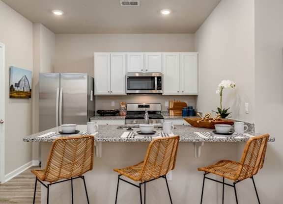 a kitchen with a counter top and three chairs