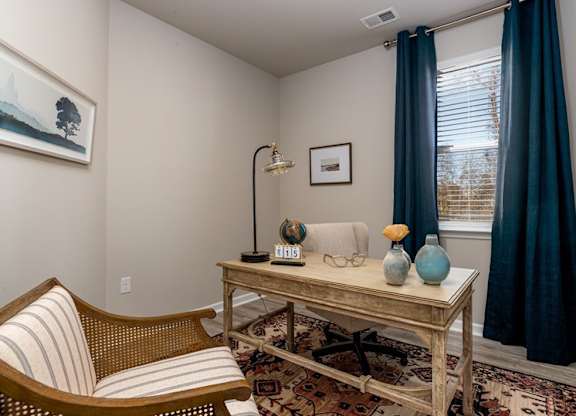 a home office with a desk chair and a window