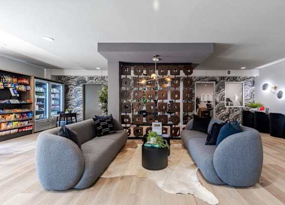 a living room with two gray couches and a wall with a mural