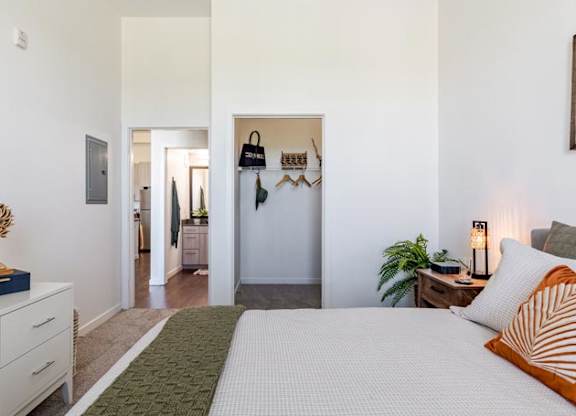 a white bedroom with a bed and a hallway