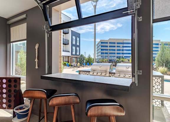 a bar with three stools in front of a large window