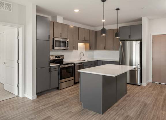 A modern kitchen with a large island and stainless steel appliances.