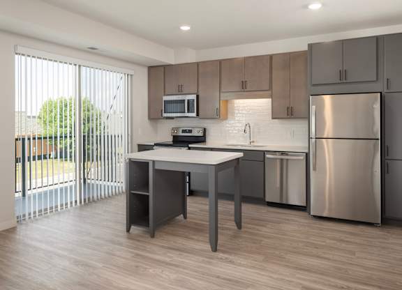 A modern kitchen with a table and stainless steel appliances.