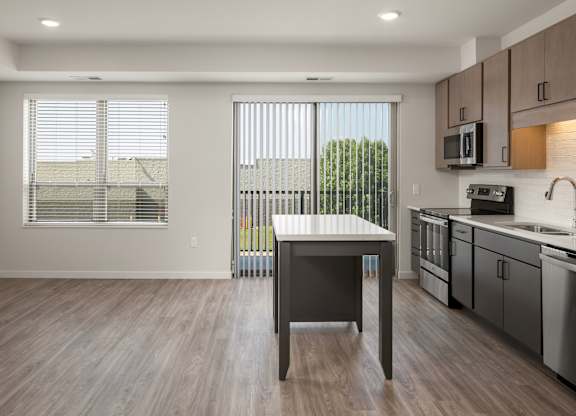 A kitchen with a table and chairs in front of a window with blinds.