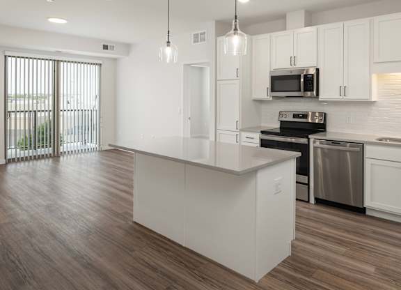 A modern kitchen with white cabinets and a wooden floor.