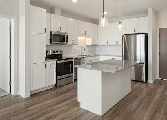 A modern kitchen with white cabinets and stainless steel appliances.