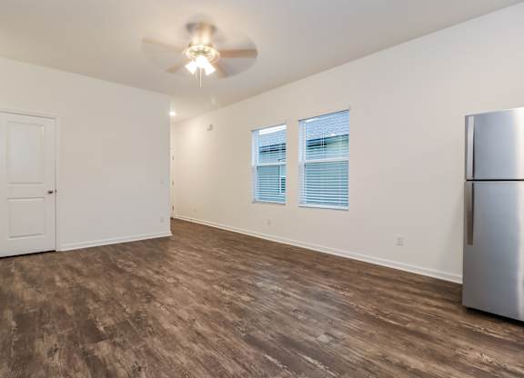 A room with a ceiling fan and a refrigerator.
