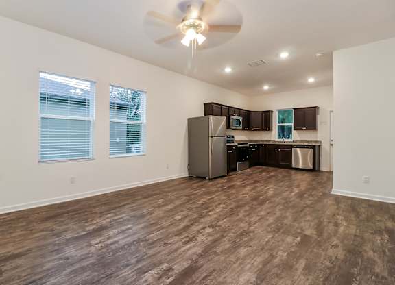 A room with a ceiling fan and wooden flooring.