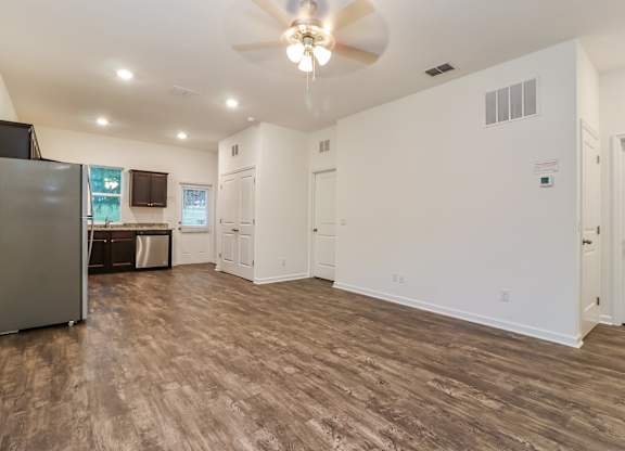 A spacious room with a ceiling fan and wooden flooring.