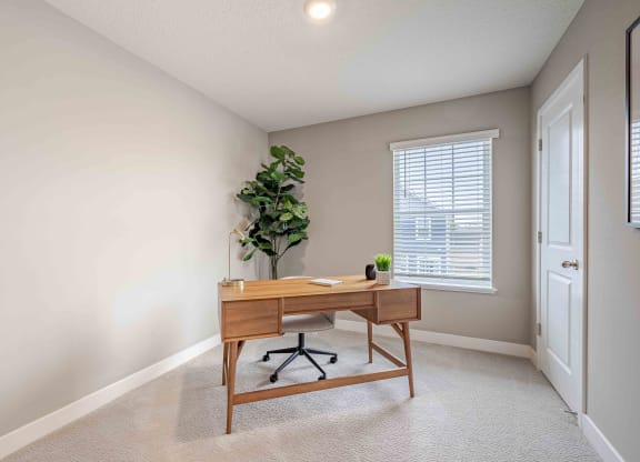 a home office with a wooden desk and a window
