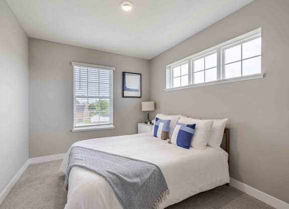 a bedroom with a bed and two windows